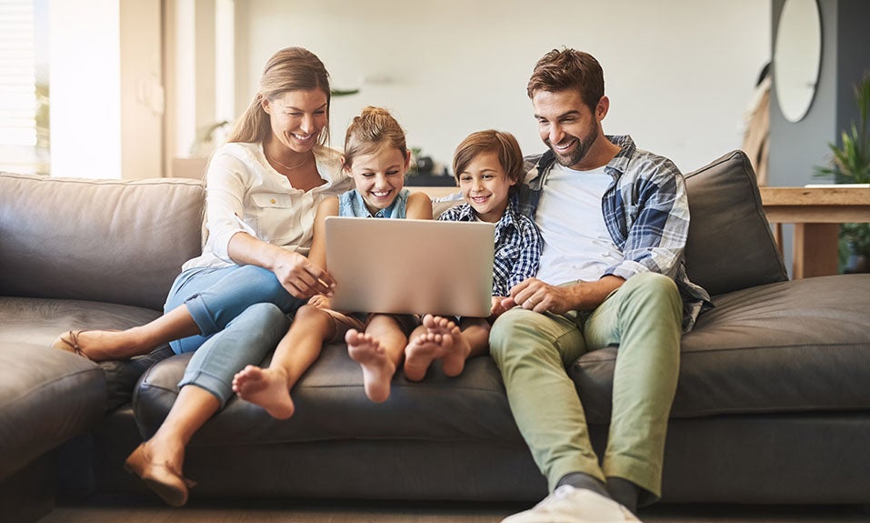 Family on couch using laptop together