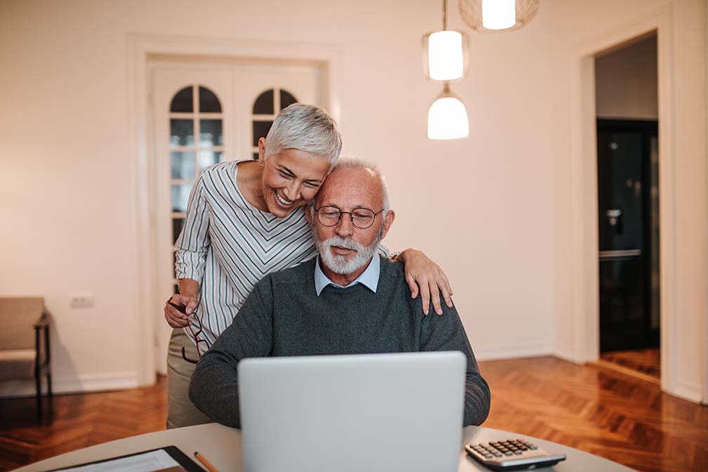 married older couple on laptop in dining room