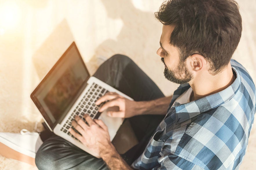 man sitting on floor using laptop